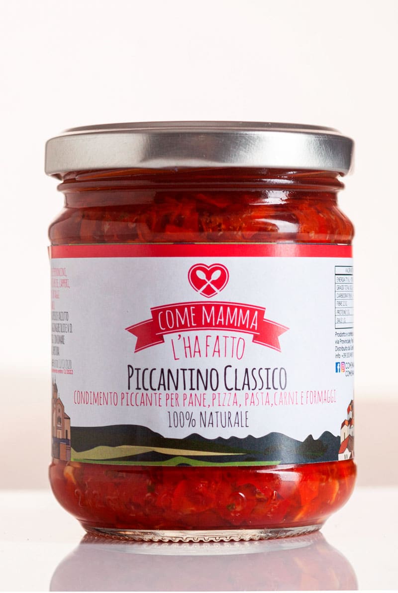 Bruschette piccanti: la ricetta con il paté di peperoncino 1 Il barattolo del Piccantino di Mamma Enza, paté di peperoncino artigianale in olio extravergine, su un tavolo di legno rustico